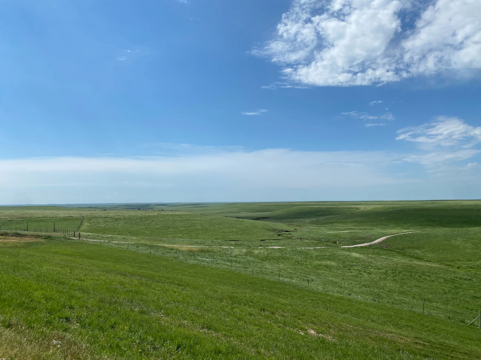 Wide-open Kansas prairie grassland rolling to the horizon under a vast sky