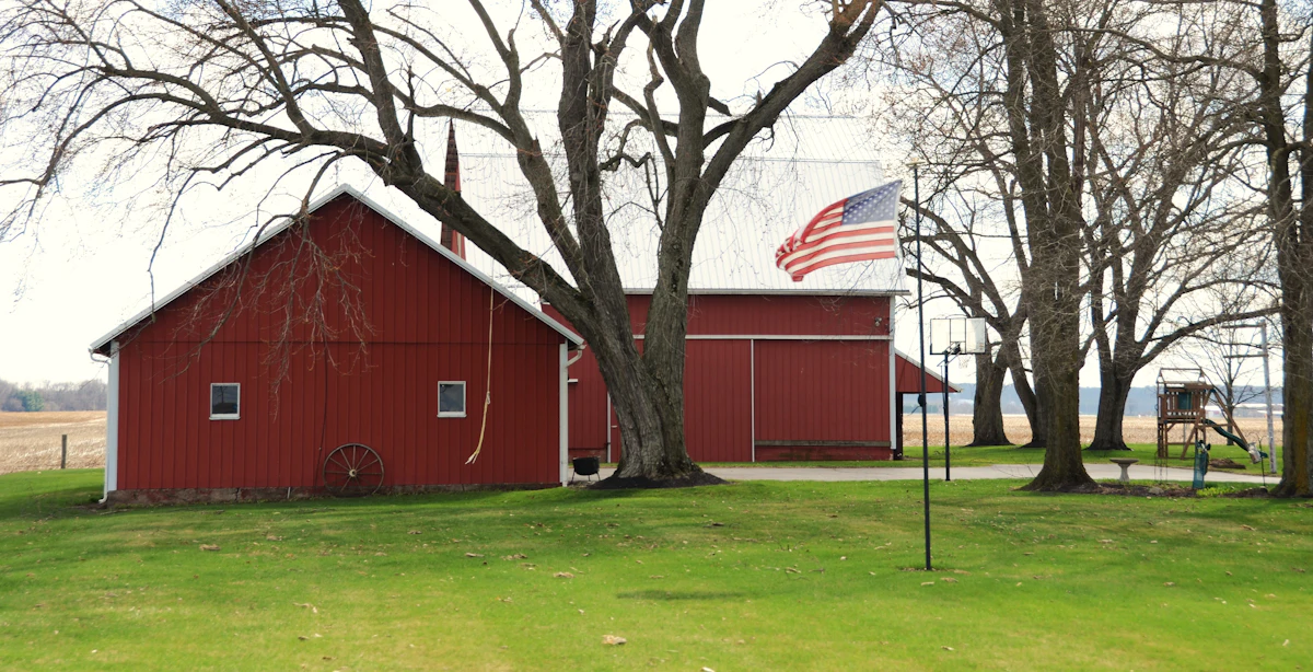A red barn flying an American flag in a rural setting