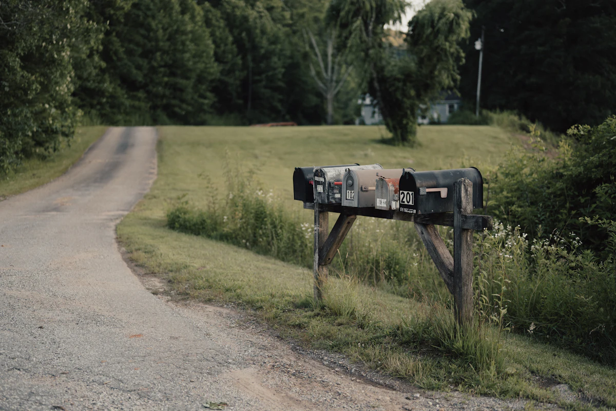 A weathered mailbox on a post along a quiet country road